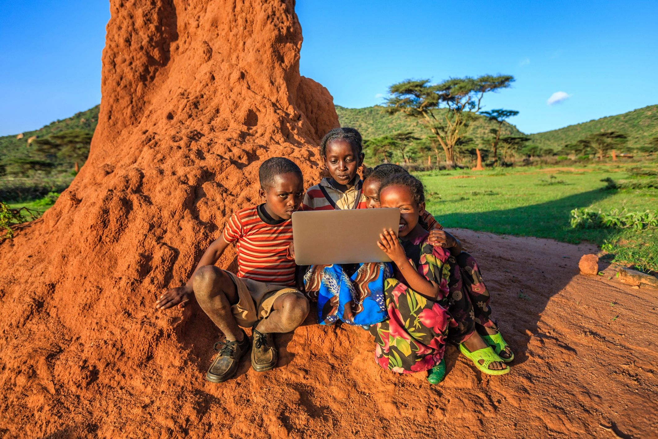 Children using a laptop in a rural village setting